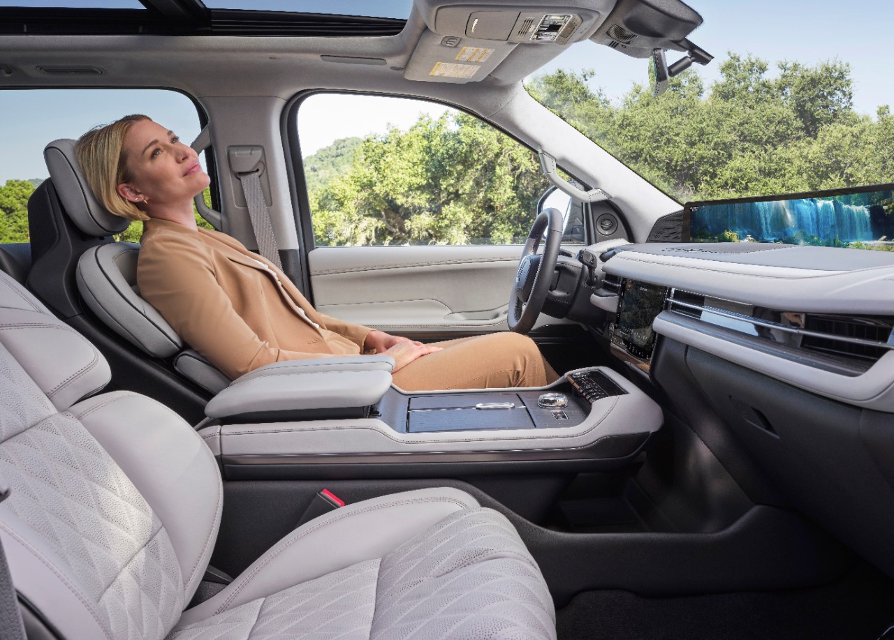 A woman reclines and relaxes in the driver's seat of a parked Lincoln SUV.